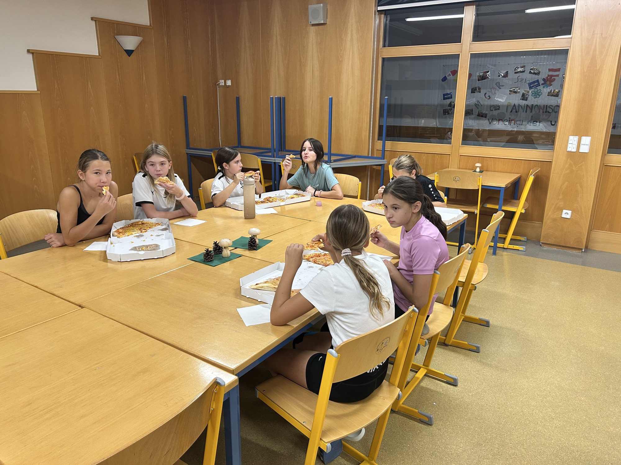Schülerinnen essen Pizza in einem Klassenzimmer in Österreich