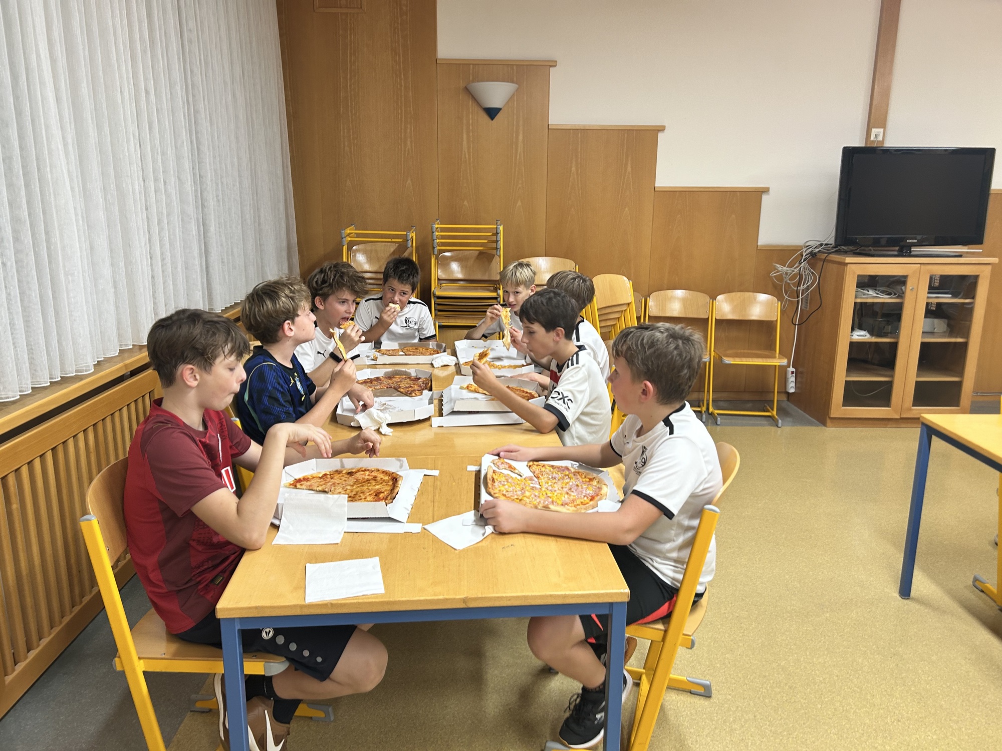 Jungs essen Pizza in einem Schulklassenraum in Österreich
